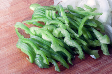 Green bell pepper, white onion and a knife on a cutting board. The vegetables are fresh and recently sliced. Concept of healthy eating and lifestyle.