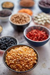 Raw lentil seeds in ceramic bowl. Composition of superfoods in background. Placed on white rusty table. Selective focus.