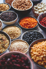 Assortment of different kinds organic natural foods and superfoods. Placed in ceramic bowls on rusty background. Above view.