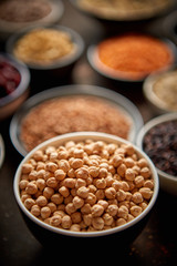 Raw peas seeds in ceramic bowl. Composition of superfoods in background. Placed on dark rusty table. Selective focus.