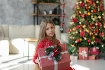 Beautiful girl near the Christmas tree with gifts