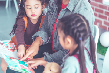 Teacher is reading story book to kindergarten students