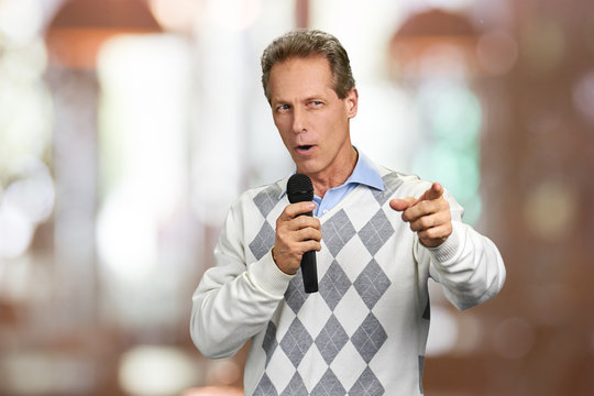 Man with microphone showing forward with finger. Man talking into microphone and gesturing. Concept of interactive discussion.