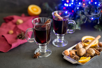 Red mulled wine in glasses with electric lights at dark background