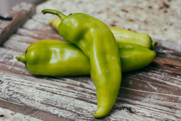 Set of green sweet peppers on wooden table. Fresh raw vegetables.
