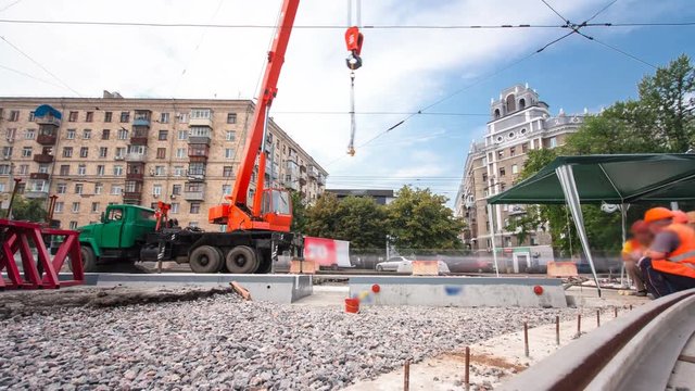 Unloading concrete plates from truck by crane at road construction site timelapse.