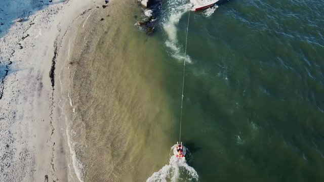 Motor boat in the sea tows a inflatable raft with men, white bird flying near