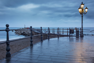 Fototapeta premium street lighter in dark morning twilight on the pier on amalfi coast in Italy
