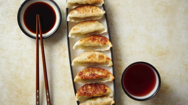 Orginal asian dumplings gyoza served in long plate with soy souce in a bowl and a cup of tea. With chopsticks. Placed on rusty background.