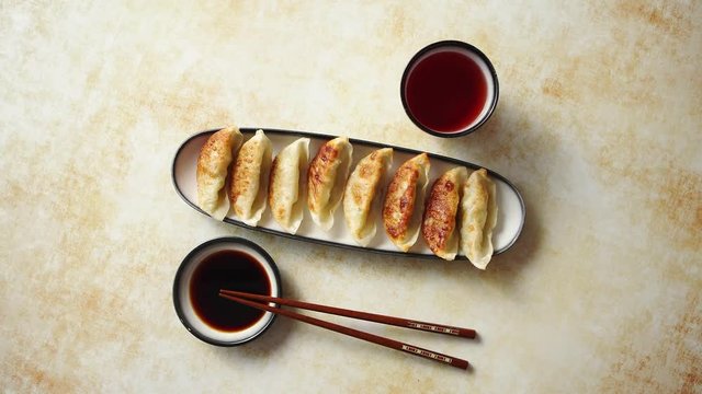 Orginal asian dumplings gyoza served in long plate with soy souce in a bowl and a cup of tea. With chopsticks. Placed on rusty background.