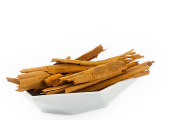 Dry cinnamon sticks in a small white ceramic dish isolated on white background