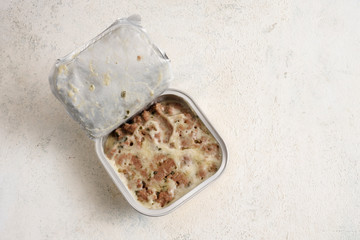 pet food with sauce in an aluminium foil tray for cats or dogs on a light background with copy space, high angle view from above