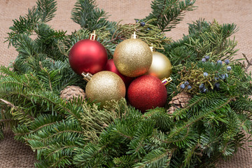 Winter holiday decoration: fraser fir table wreath centerpiece with cones, juniper and Christmas tree balls on burlap background