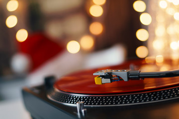 Image of Christmas. Turntable vinyl record player. Sound technology for DJ to mix & play music. Retro audio vinyl record on a background of Christmas decorations