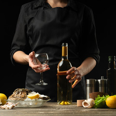 Chef pours, tastes Italian dry wine with oysters with lemon on a black background, the concept of seafood, wine, menus, recipes, restaurant and hotel
