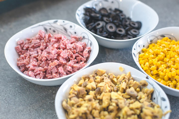 Pizza ingredients, corn, olive and salami in coup. 
