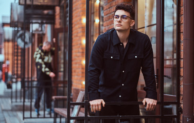 A young handsome man standing near a cafe outdoors.