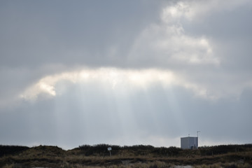 Plakat sun light in the clouds over a dune 
