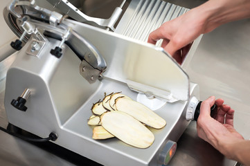 Chef's work on a slicer, slicing vegetables