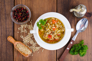 White bowl of chicken and wild rice soup with vegetables