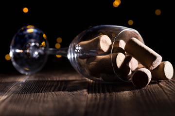 wine glass lies on a wooden dark background with cork stoppers inside with beautiful bokeh
