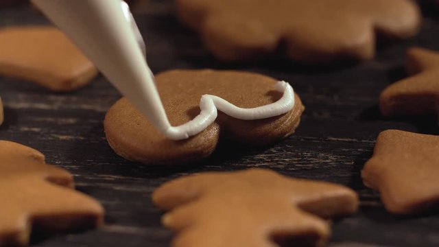 Close up garnishing homemade gingerbread heart. Decoration process of Christmas cookies. Family culinary and traditions concept