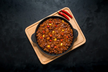 Chili con carne in frying pan on dark background. Texas chili.
