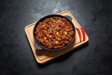 Chili con carne in frying pan on dark background. Texas chili.
