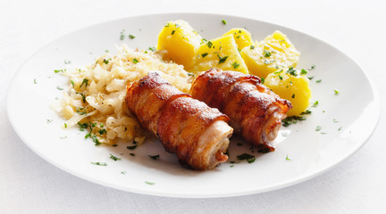 roasted rabbit belly and bacon roulades  garnished with potato and cabbage sprinkled with parsley