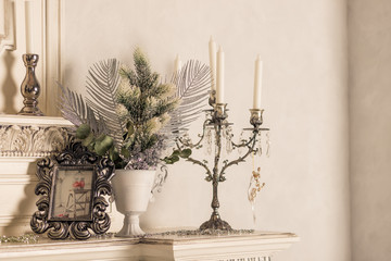 Christmas decoration with candles on shelf, white wall.Retro silver candlesticks with white candles.Toned retro image.scandinavian room interior.Living room interior