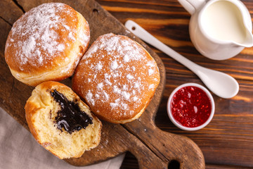 Tasty sweet sugary chocolate donuts with raspberry jam and milk