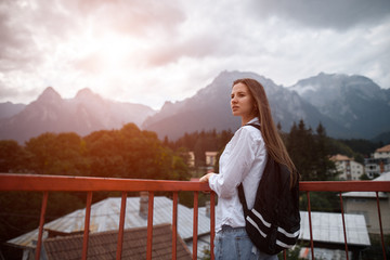 Young hipster girl with backpack on mountains background