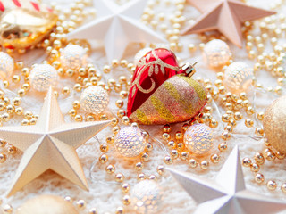 Fototapeta na wymiar Christmas and New Year star decorations on white knitted background. Metal light bulbs with delicate pattern, golden beads and red decorative heart.