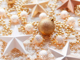 Christmas and New Year star decorations on white knitted background. Metal light bulbs with delicate pattern, golden beads and balls.