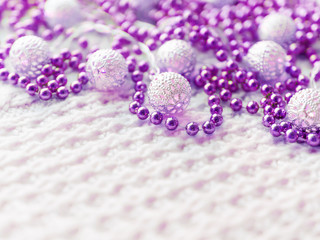 Christmas and New Year decorations on white knitted background. Metal light bulbs with delicate pattern, purple beads.