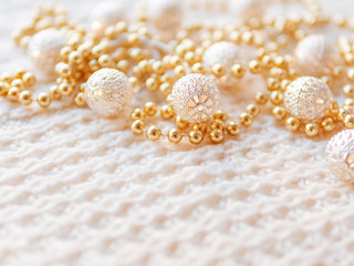 Christmas and New Year decorations on white knitted background. Metal light bulbs with delicate pattern, golden beads.
