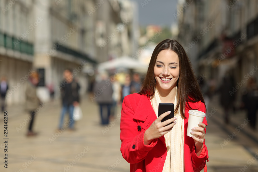 Wall mural front view of a happy woman using phone in winter