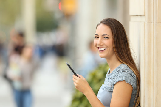 Girl using a smart phone on the street looking at you