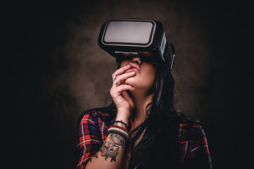 Tattooed girl wearing a red unbuttoned checked shirt wearing a VR headset.
