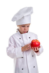 Amazed chef girl in a cap cook uniform, holding and examining the red apple. Human emotions, facial expression feeling, attitude. Portrait image