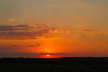 Beautiful calm sunset background. Nature and ecology concept. Golden evening sunset over the dark trees.