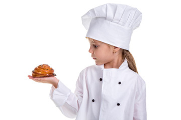 Chef girl in a cap cook uniform, holding the bun in the right hand. Looking at the bun