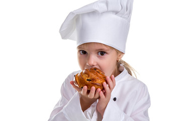 Closeup of a chef girl in a cap cook uniform, holding and biting the tasty bun. Looking at the camera
