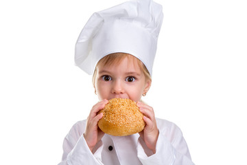Cute chef girl in a cap cook uniform, biting the bread with sesame. Looking at the straight to the camera