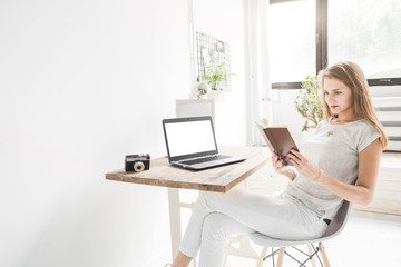 Young business woman working at home and reading a book. Creative Scandinavian style workspace