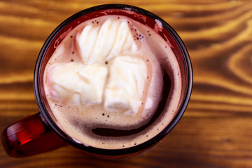 Cup of hot chocolate with melted marshmallow on wooden table