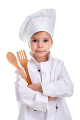 Smirking girl chef white uniform isolated on white background. Holding wooden spoon and fork in the folded hands. Portrait image