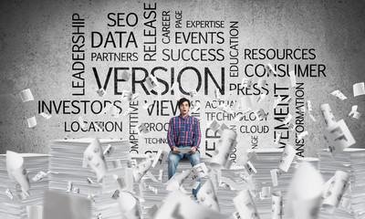 Attractive man sitting on pile of paper documents.