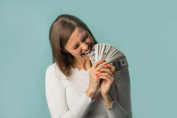 beautiful young girl biting teeth with dollars on a blue background