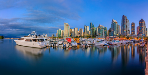 Sunset panorama at Coal Harbour in Vancouver British Columbia with downtown buildings boats and reflections in the water